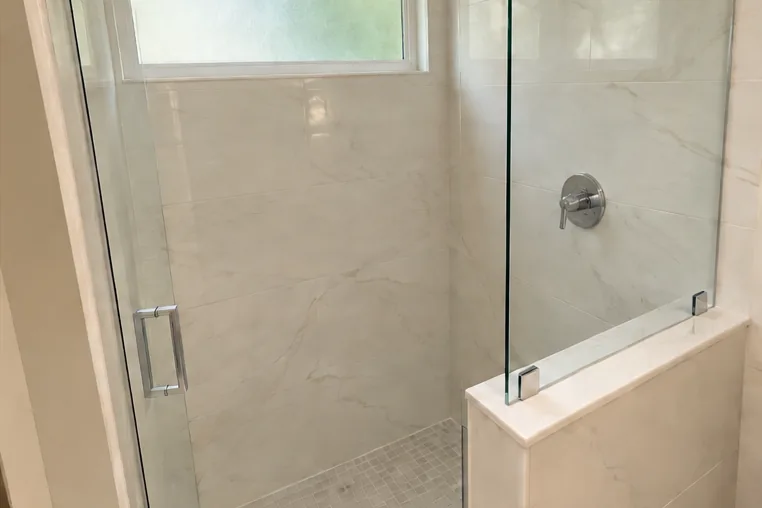 After: the same shower finished with tile and a frameless glass enclosure