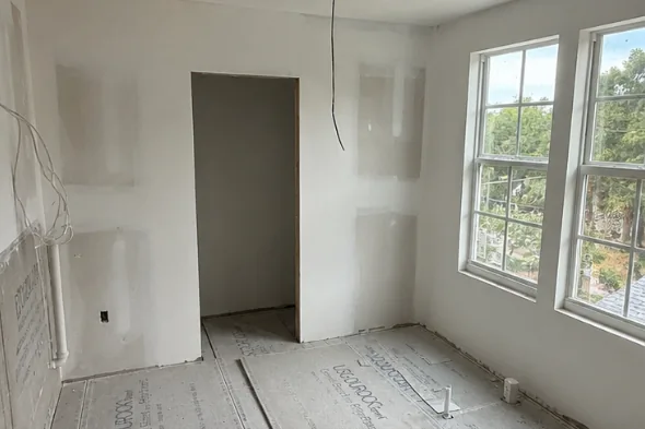 Before: bathroom at drywall stage with bare walls and an unfinished floor