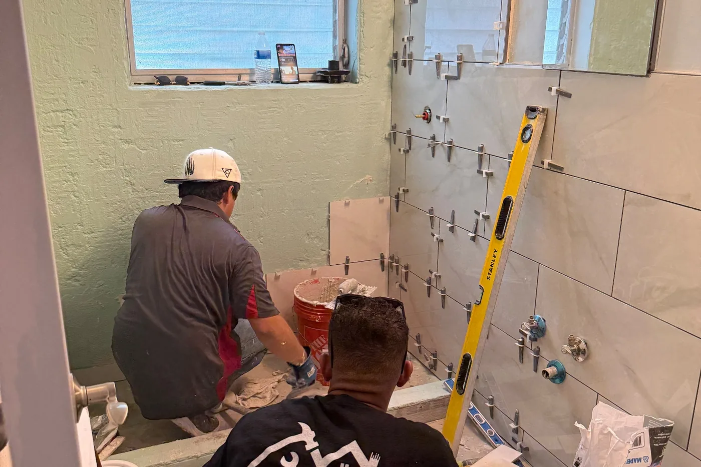 Before: the crew setting tile on the bathroom walls mid-remodel